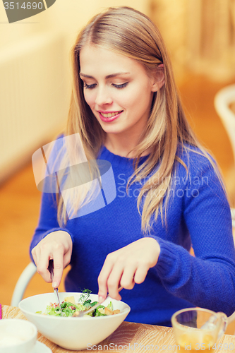 Image of happy young woman having dinner at restaurant