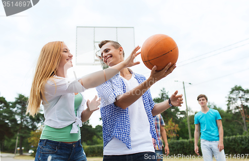 Image of group of happy teenagers playing basketball