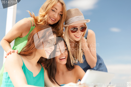 Image of smiling girls looking at tablet pc in cafe