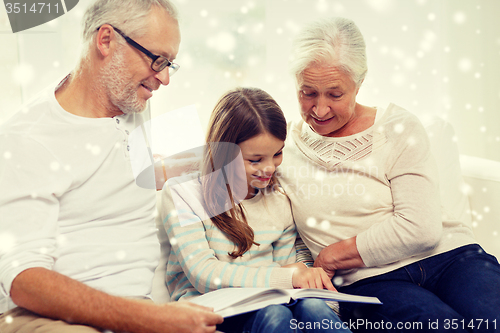 Image of smiling family with book at home