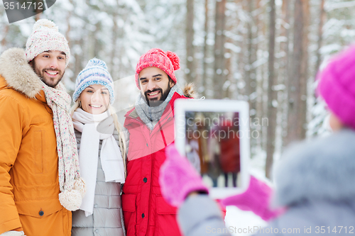 Image of smiling friends with tablet pc in winter forest