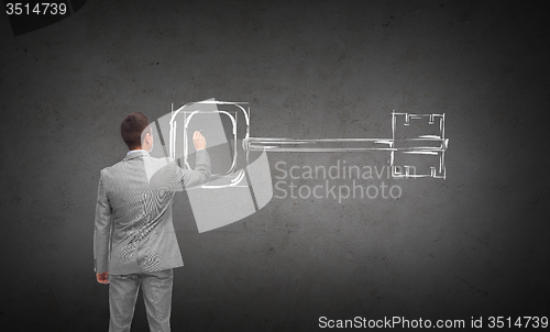 Image of businessman drawing key from back