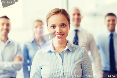 Image of smiling businesswoman with colleagues in office