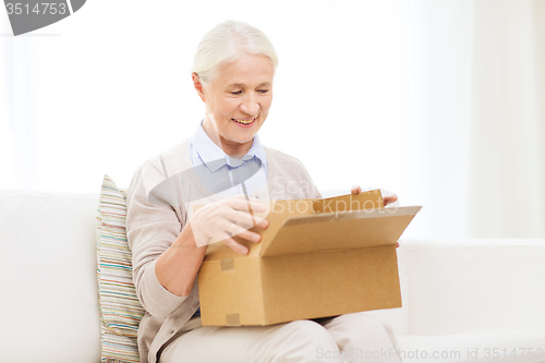 Image of happy senior woman with parcel box at home