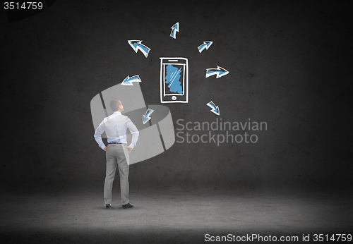 Image of businessman looking smartphone over concrete wall