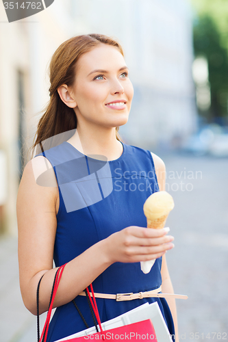 Image of woman with shopping bags and ice cream in city