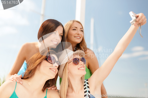 Image of smiling girls taking photo in cafe on the beach