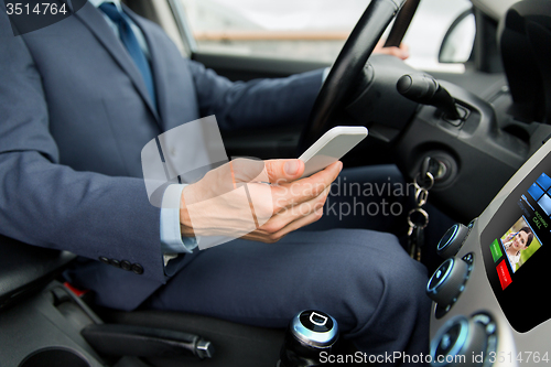 Image of close up of man with smartphone driving car