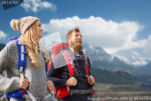 Image of happy couple with backpacks hiking over mountains