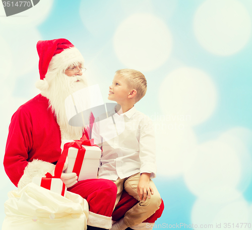 Image of smiling little boy with santa claus and gifts