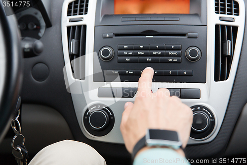 Image of close up of male hand turning on radio in car