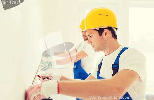 Image of group of builders with measuring tape indoors