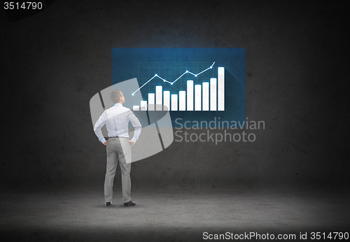 Image of businessman looking at chart over concrete room