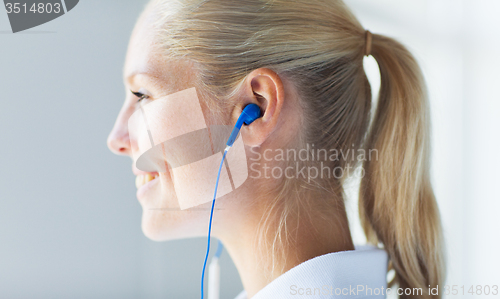 Image of close up of happy woman in earphones at home