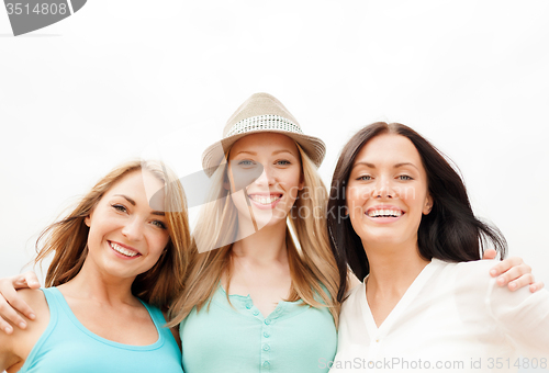 Image of group of smiling girls chilling on the beach