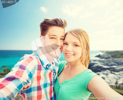 Image of smiling couple with smartphone on summer beach