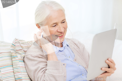 Image of senior woman with tablet pc and earphones at home