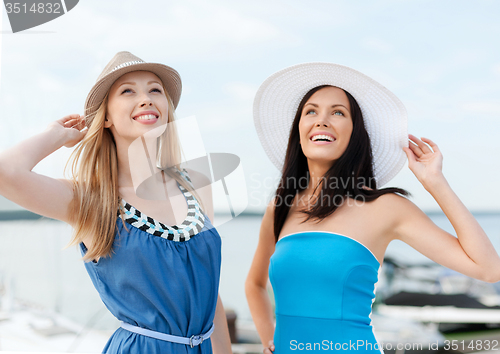 Image of girls in dresses with hats on the beach