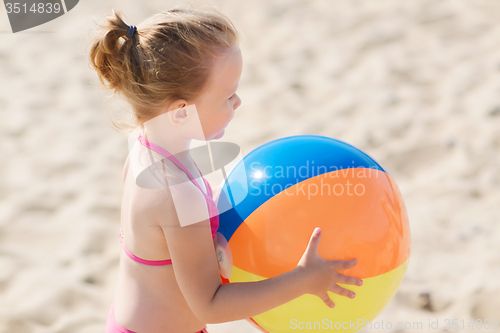 Image of happy little girl playing inflatable ball on beach