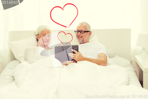 Image of happy senior couple with tablet pc at home