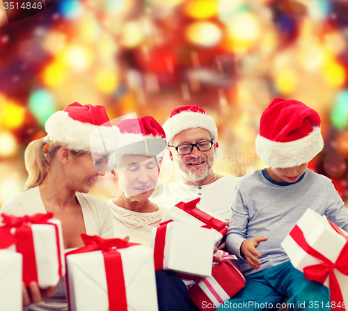 Image of happy family in santa helper hats with gift boxes