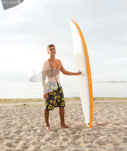 Image of smiling young man with surfboard on beach