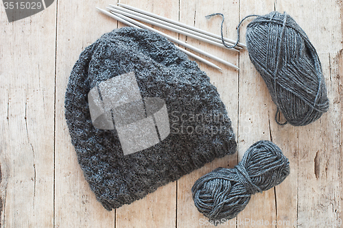 Image of wool grey hat, knitting needles and yarn