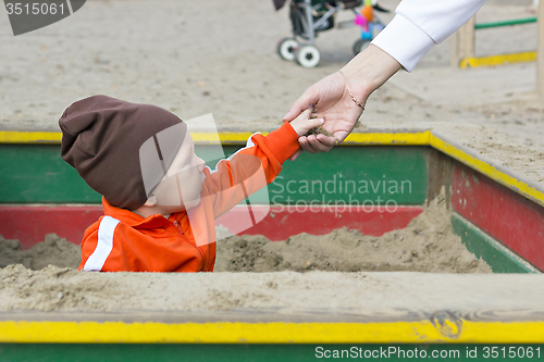 Image of Small child in sandbox gives sand