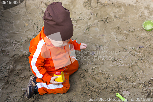 Image of Baby boy is playing in sandbox