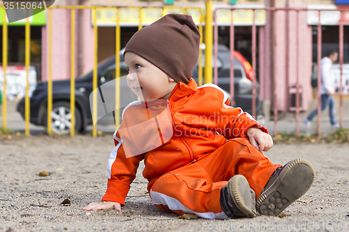 Image of Small funny boy sits on ground