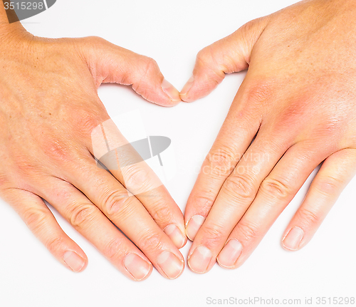 Image of Adult person creating heart with hands towards grey white