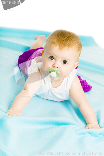 Image of baby girl with pacifier crawling on the blue coverlet