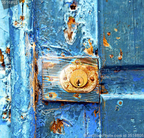 Image of rusty metal nail dirty stripped paint in the blue wood door and 