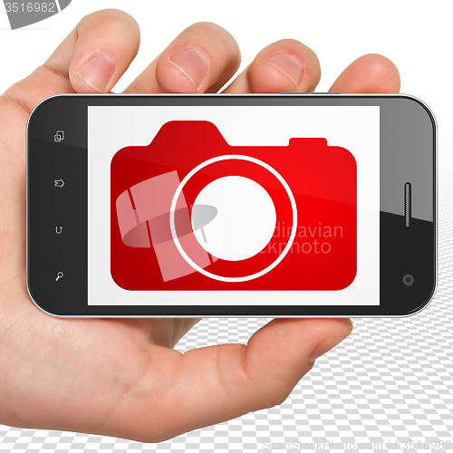 Image of Travel concept: Hand Holding Smartphone with Photo Camera on display