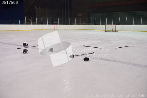 Image of hockey sticsk and puck on ice