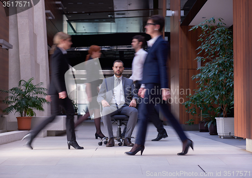 Image of business man sitting in office chair, people group  passing by