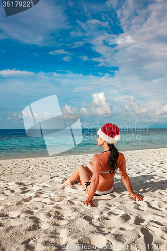 Image of Woman in santa hat on the beach