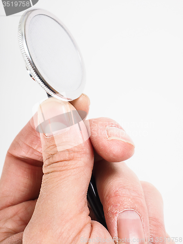 Image of Closeup of hand holding a stethoscope towards bright background