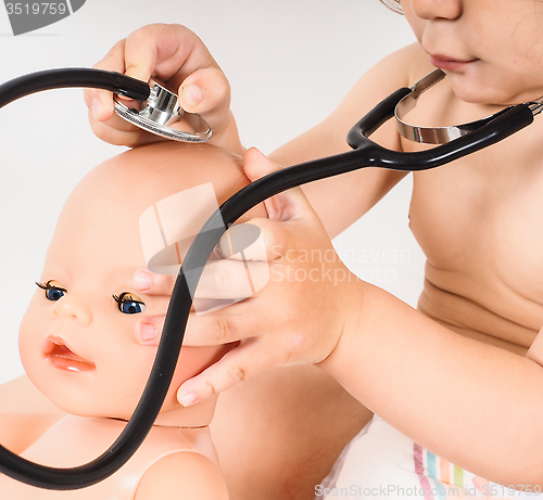 Image of Toddler running a health check on a hairless doll with a stethos