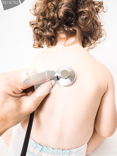 Image of Child at pediatrician with health check using stethoscope on bac