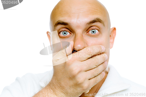 Image of Bald frightened man in a white jacket covers her mouth with his 