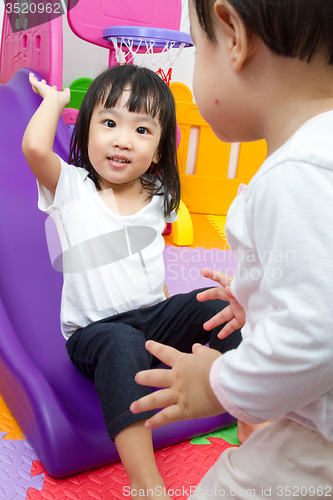 Image of Asian Chinese little sister and brother playing on the slide