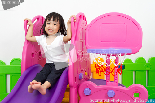 Image of Asian Chinese little girl playing on the slide