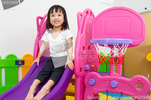 Image of Asian Chinese little girl playing on the slide