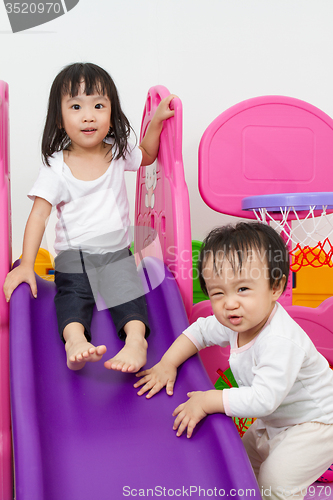 Image of Asian Chinese little sister and brother playing on the slide