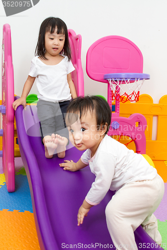 Image of Asian Chinese little sister and brother playing on the slide