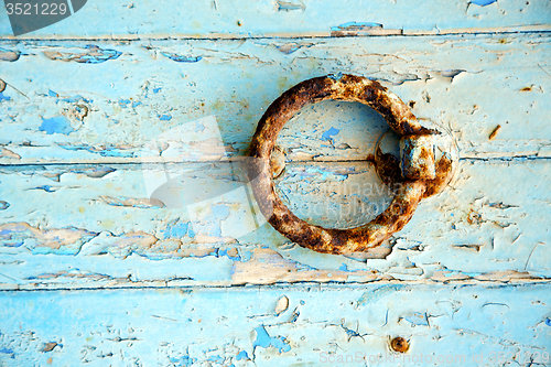Image of rusty  paint in the blue wood door and morocco knocker