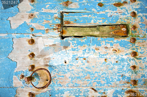 Image of rusty   paint in the blue wood door and morocco knocker