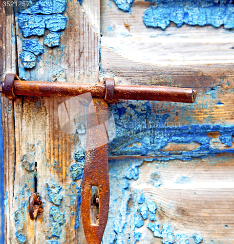 Image of rusty metal     nail dirty stripped paint in the blue wood door 