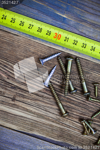 Image of several different screws and yellow measuring tape